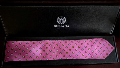 A pink silk necktie with a repeating circular pattern, displayed inside an open black Bellavita gift box.