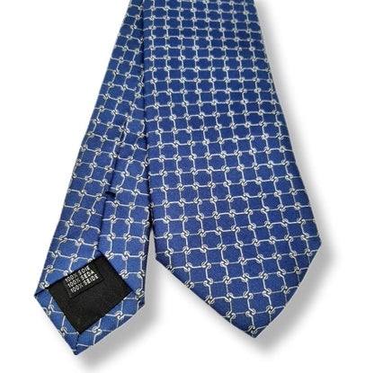A blue silk necktie with a repeating white geometric interlocking-link pattern, shown folded on a white background with a black size label visible at the tip.